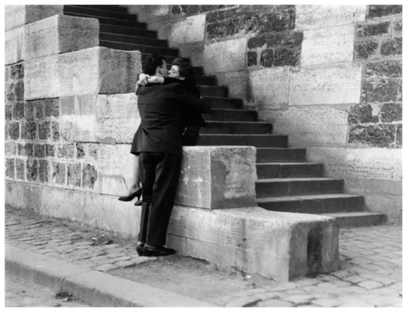 A couple embraces on a quiet stone stairway 