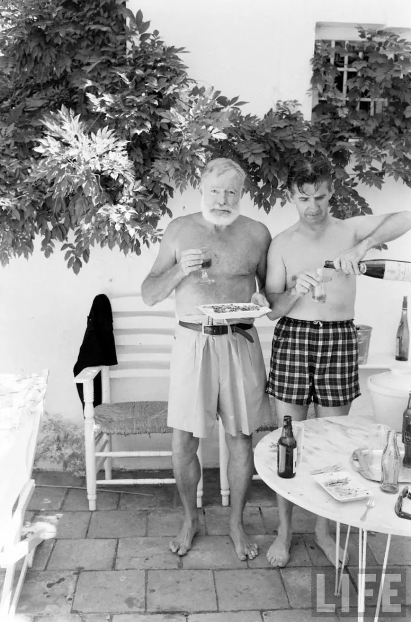 Ernest Hemingway and bullfighter Antonio Ordóñez Araujo drink wine by the pool
