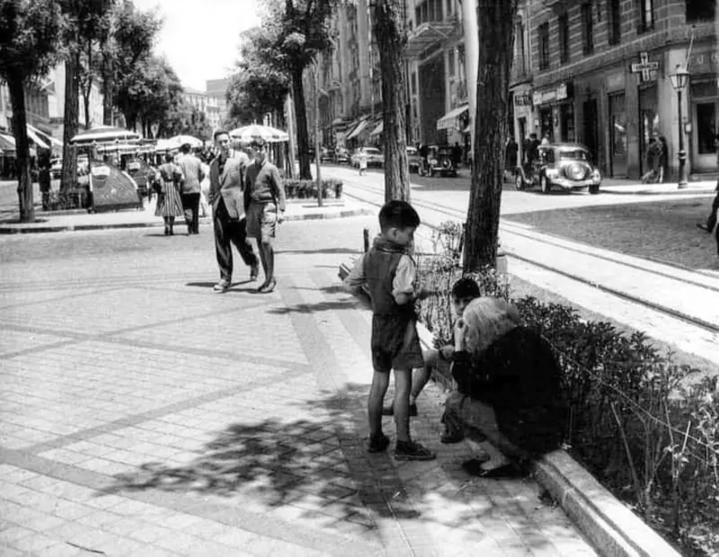 Abuela con sus nietos sentada en un bordillo