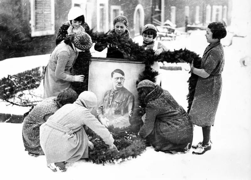 Girls decorating a portrait of Hitler for Christmas