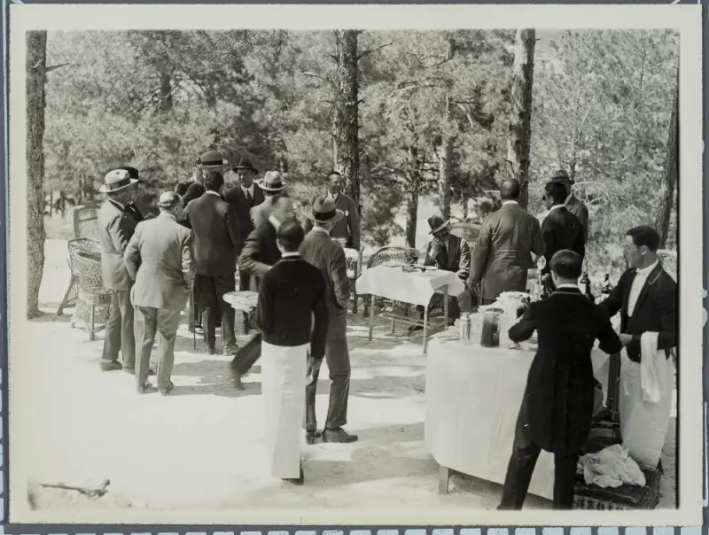Alfonso XIII sentado al aire libre tomando un refrigerio