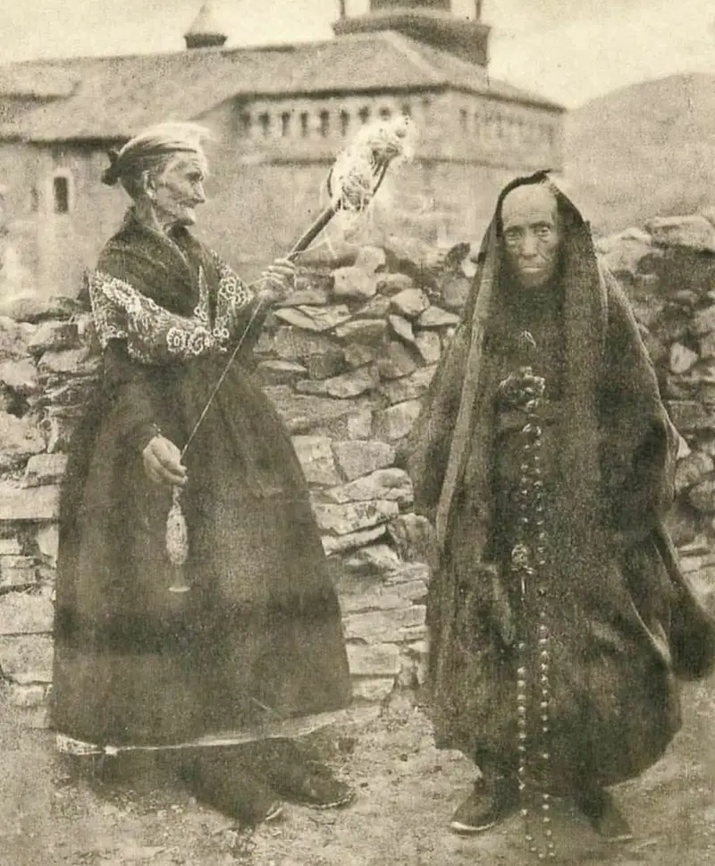 Mujer hilando y devota con el rosario.