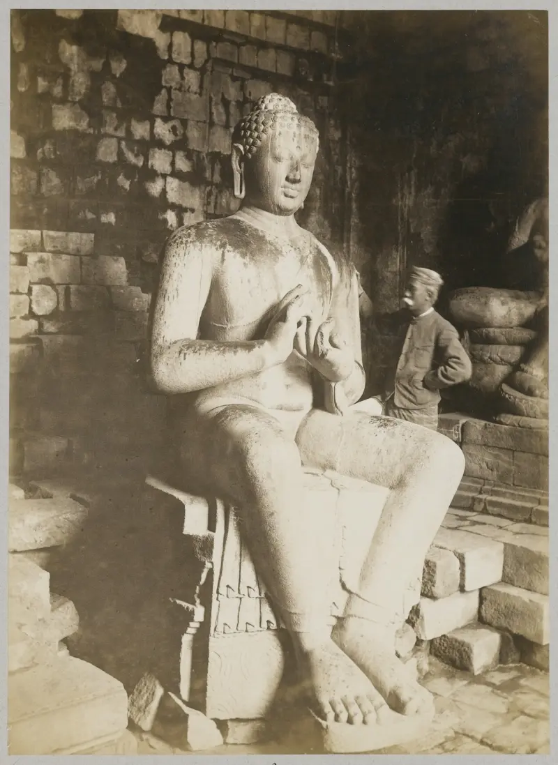 The photographer K. Céphas at the Buddha sculpture in Tjandi Mendoet
