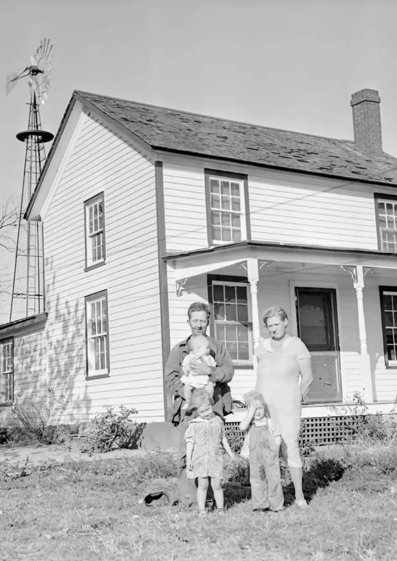 A farming family poses in front of their home