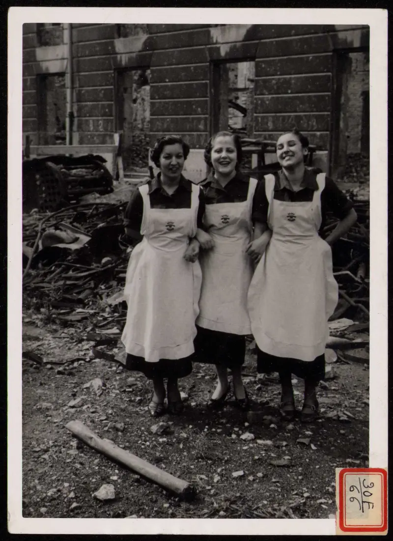 FALANGISTAS DEL AUXILIO SOCIAL ANTE EDIFICIOS BOMBARDEADOS