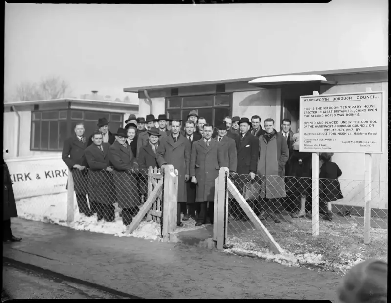 Dignitaries pose in front of the 100,000th temporary house