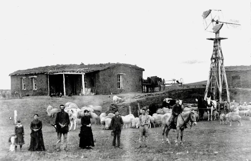 A family, a sod house, and a windmill.