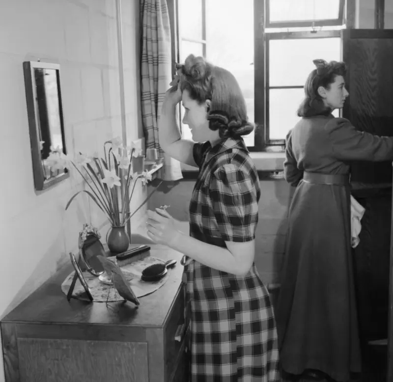 A female war worker fixes her hair
