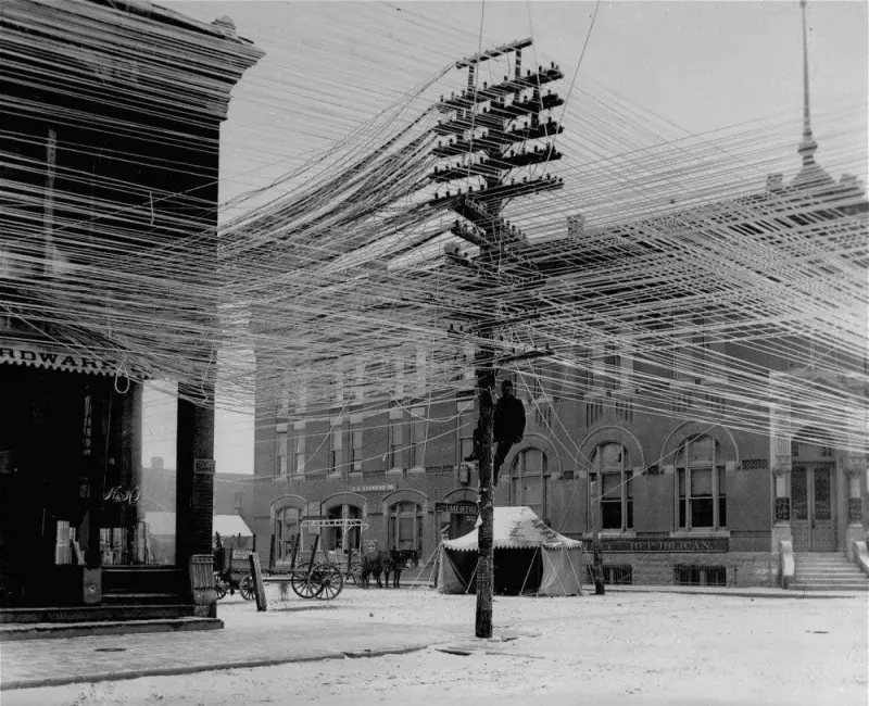View of a lineman working on power. Telephone lines at an intersection in Pratt