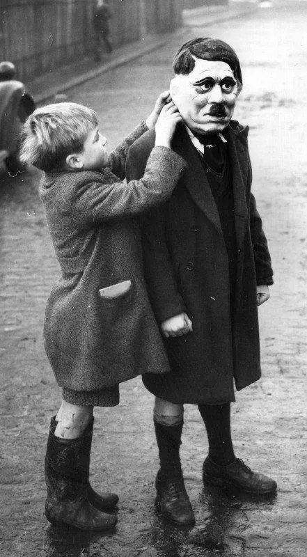 A Boy Helps His Friend Put On Hitler's Mask