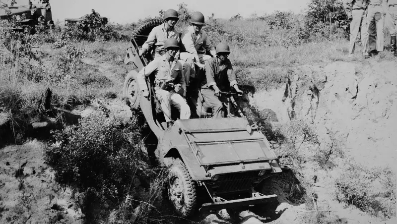 Military academy cadets and U.S. Army soldiers ride in a jeep near Fort Benning