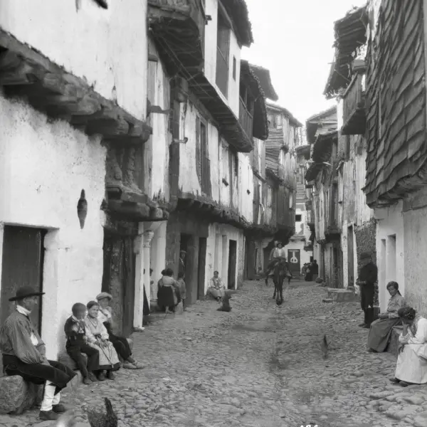 Vista de una calle, con los vecinos sentados en las puertas de las casas.
