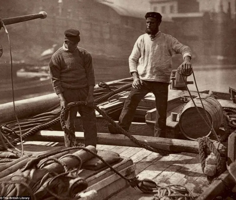 Two Sailors head down the  Thames river in a barge