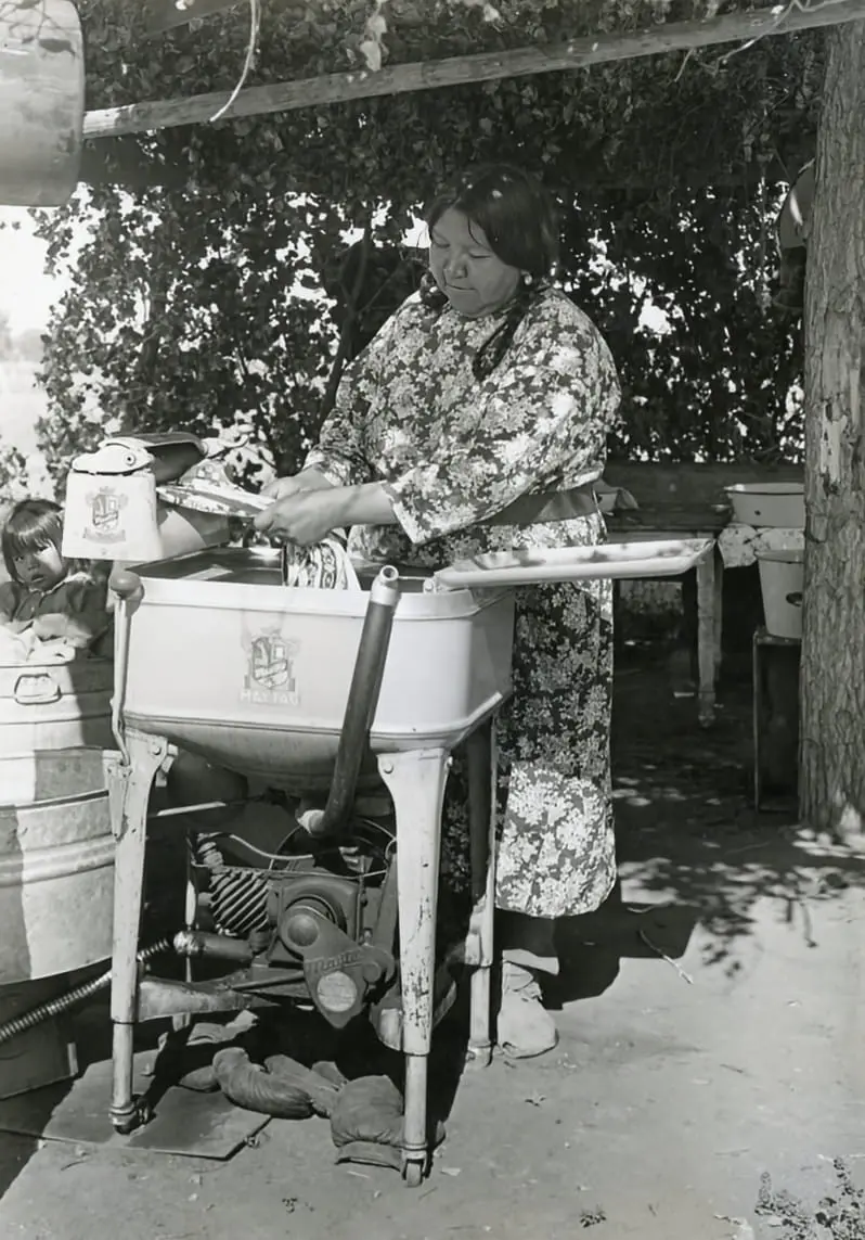 Native American woman using a washing machine.