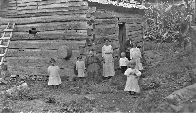 A family at their newly-built log cabin