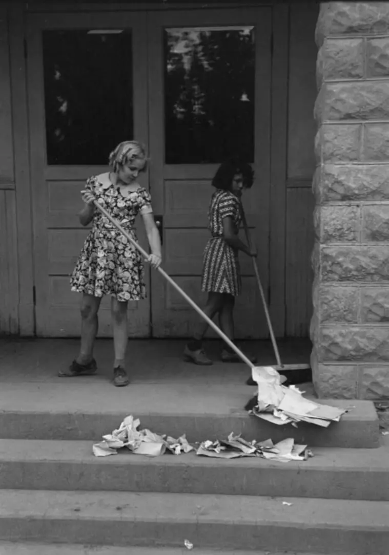 Schoolchildren cleaning up around the schoolroom. 