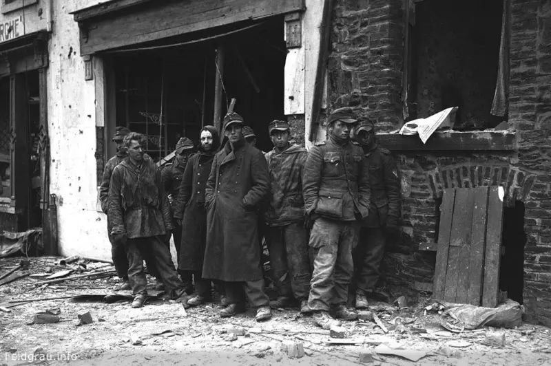 German soldiers stand in ruins on Rue Bastogne after they were captured by the U.S. 4th Panzer Division