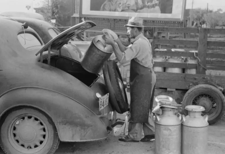 Loading empty milk cans into back of car