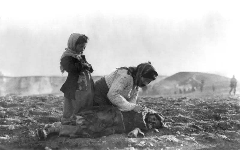An Armenian woman kneeling beside a dead child