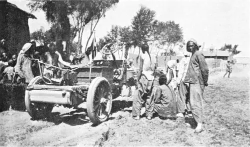 Locals look at an Itala car in the courtyard of a caravanserai
