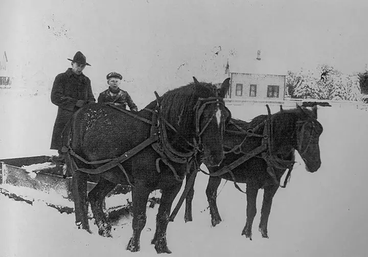 Fred and Roy Johnson ride a sleigh-like contraption known as the Stone Boat
