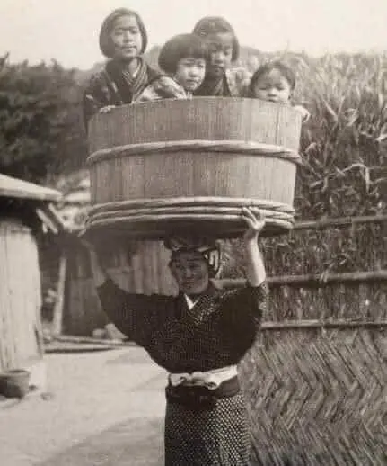Carrying her children in a bucket on her head