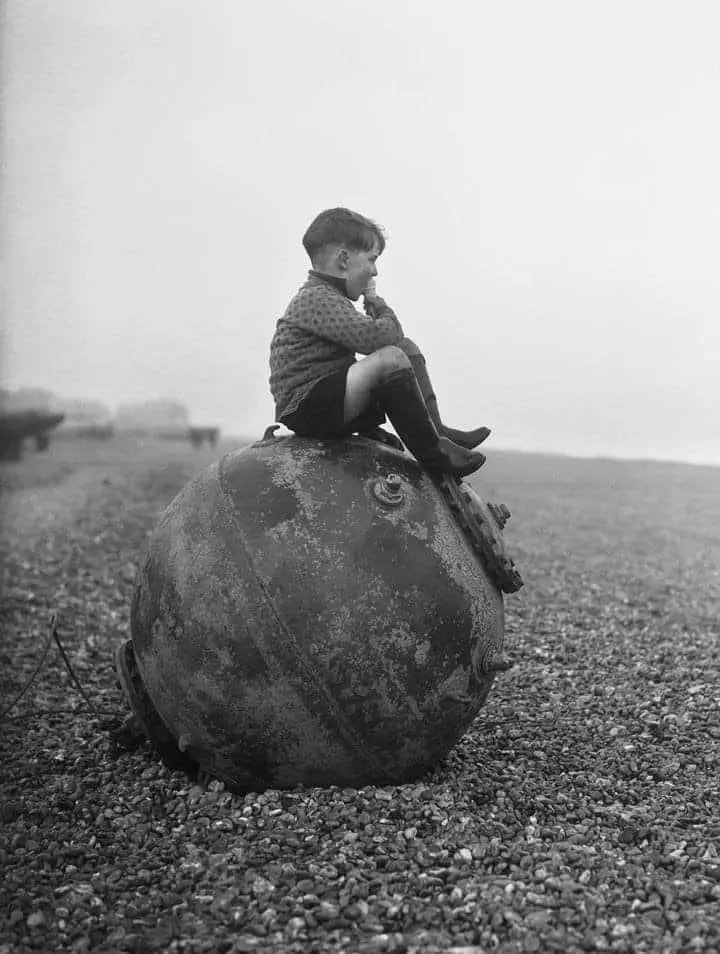 A boy enjoys his ice cream as he sits on a sea mine