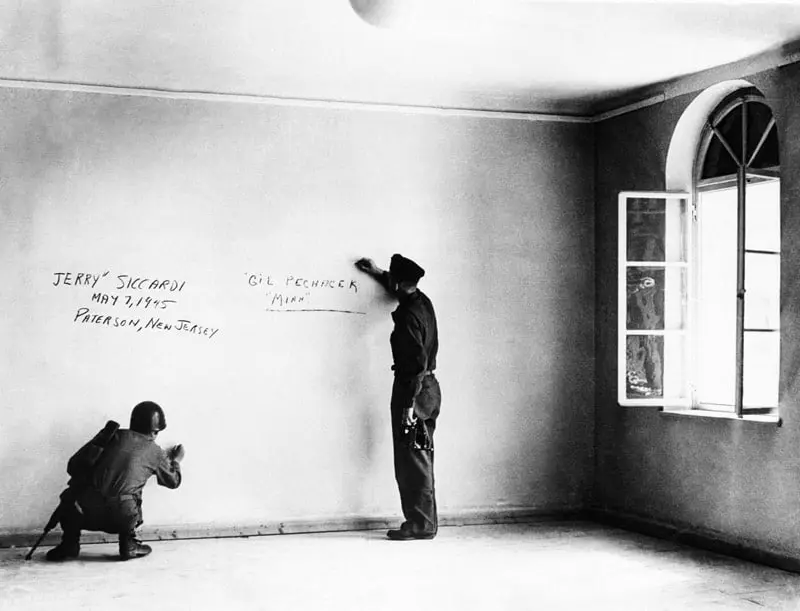American soldiers write their names in the bedroom where Adolf Hitler was born